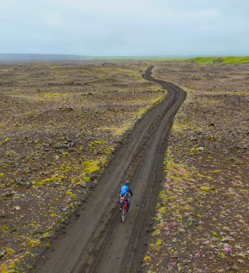 Cyclist riding past moss-covered lava fields near Mount Hekla in southern Iceland